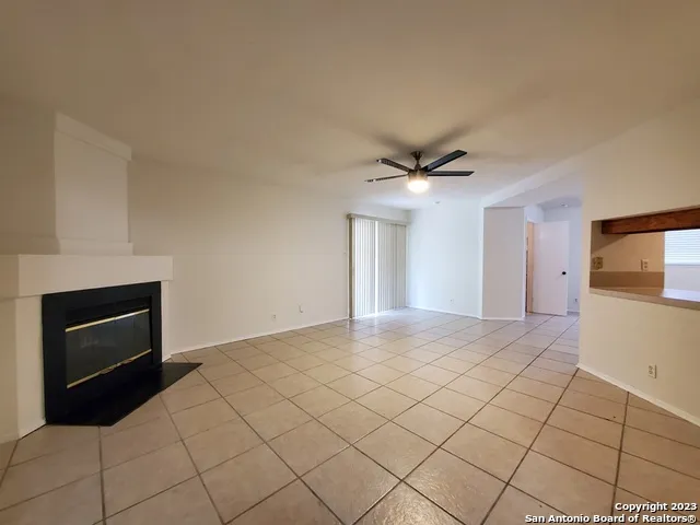 a view of an empty room and kitchen space with a fireplace