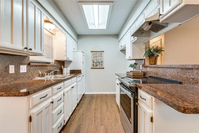 a kitchen with granite countertop a sink stove and cabinets