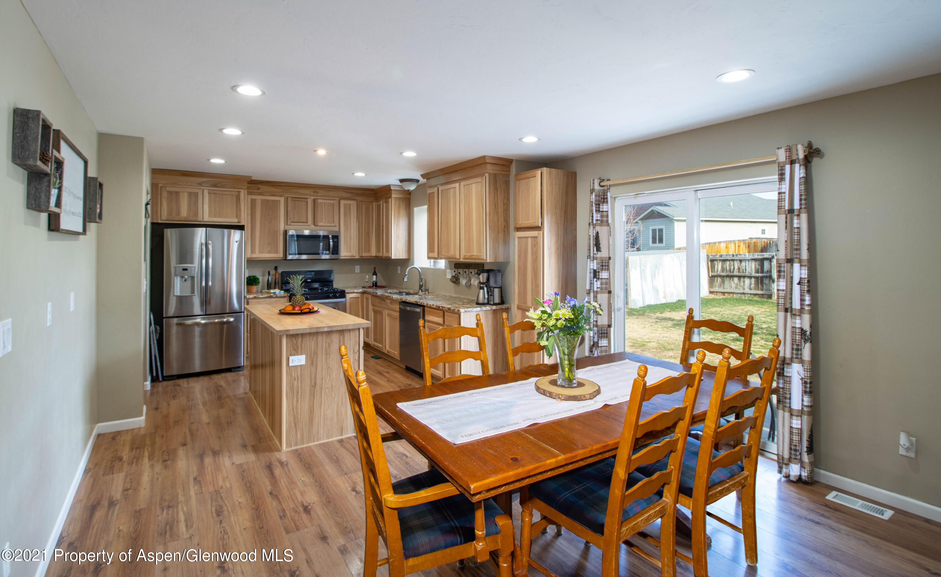 1280 East 18th Way Rifle, CO 81650 - Photo 4 of 18 a kitchen with stainless steel appliances kitchen island granite countertop a refrigerator a stove and a dining table with wooden floor
