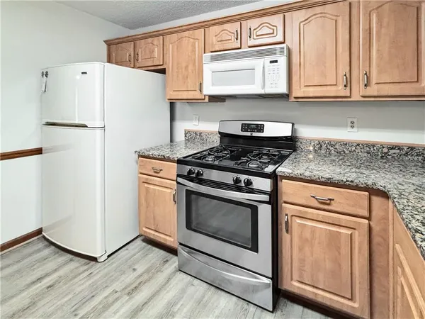 a kitchen with granite countertop white cabinets and white appliances