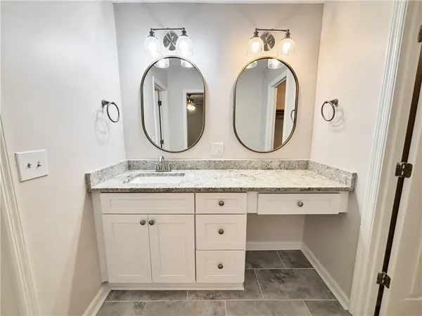 a bathroom with a granite countertop double vanity sink and a mirror