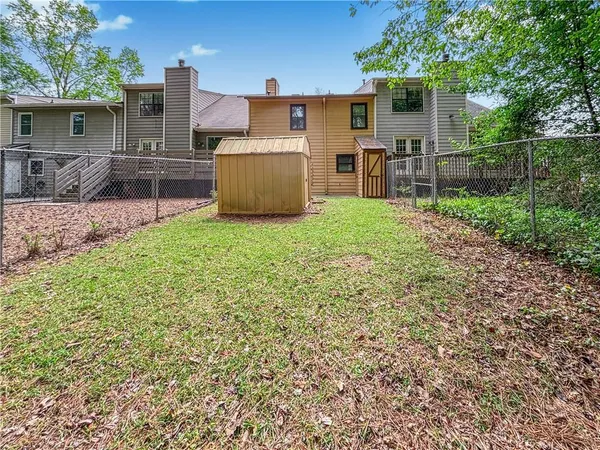 a view of a backyard with wooden fence and large trees