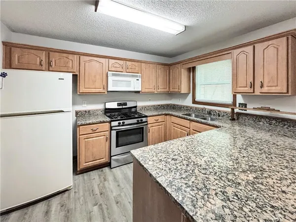 a kitchen with granite countertop a sink stove and refrigerator