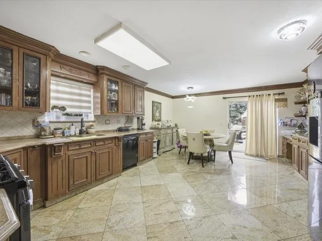 a large white kitchen with lots of counter top and dining table