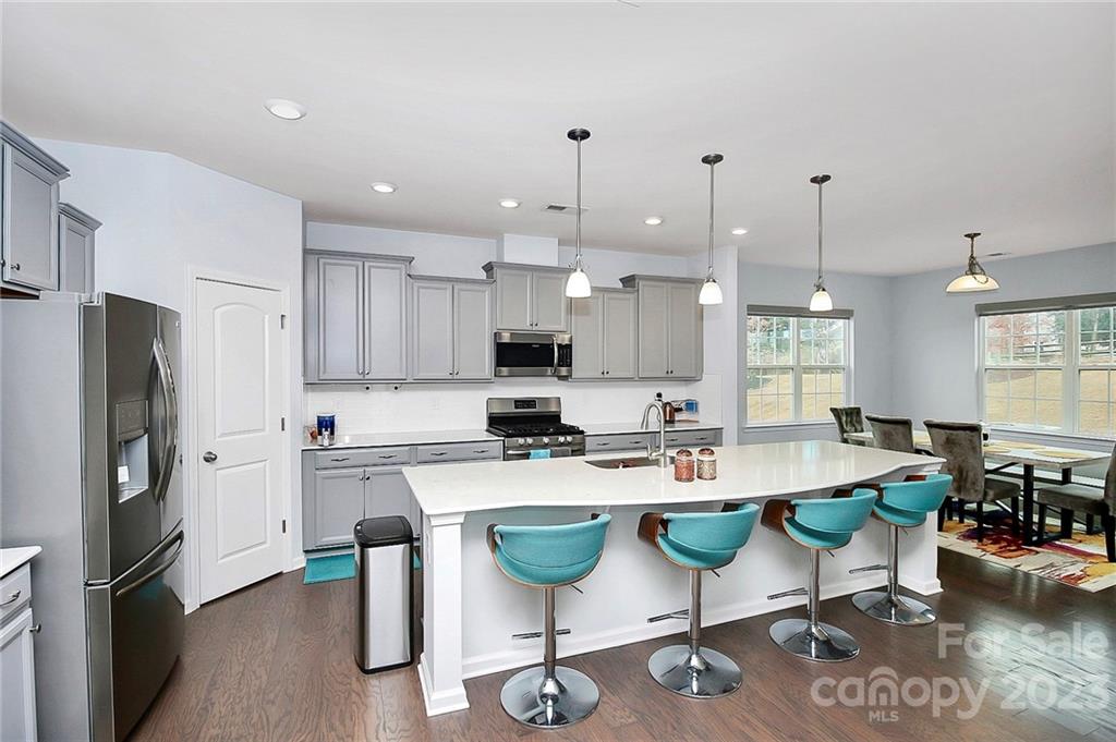 227 Houston Blair Road Matthews, NC 28104 - Photo 14 of 39 a kitchen with stainless steel appliances granite countertop a stove a refrigerator a kitchen island a dining table and chairs with wooden floor