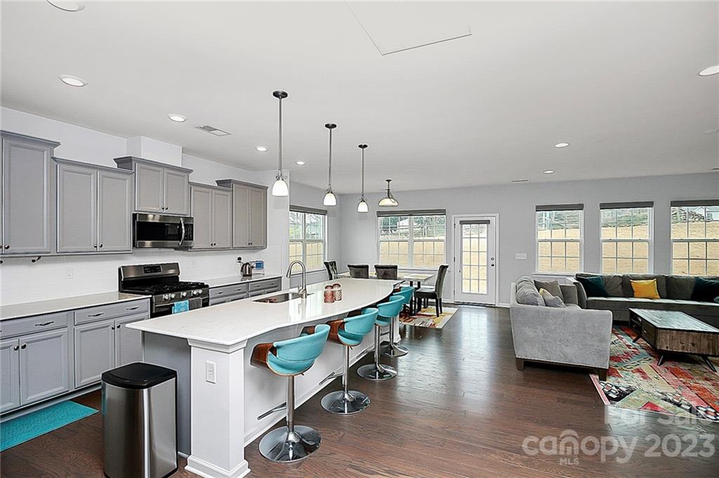 227 Houston Blair Road Matthews, NC 28104 - Photo 3 of 39 a kitchen with stainless steel appliances kitchen island granite countertop a stove a sink a dining table and chairs with wooden floor