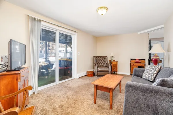 a living room with furniture a flat screen tv and a refrigerator