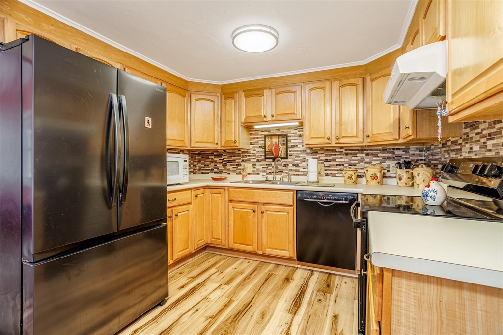 113 Parker Road, Unit 1 Lancaster, MA 01523 - Photo 6 of 30 a kitchen with stainless steel appliances granite countertop a refrigerator a sink dishwasher a stove with wooden cabinets and floor