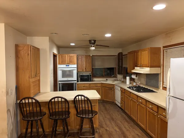 a kitchen with stainless steel appliances granite countertop a table chairs sink and cabinets