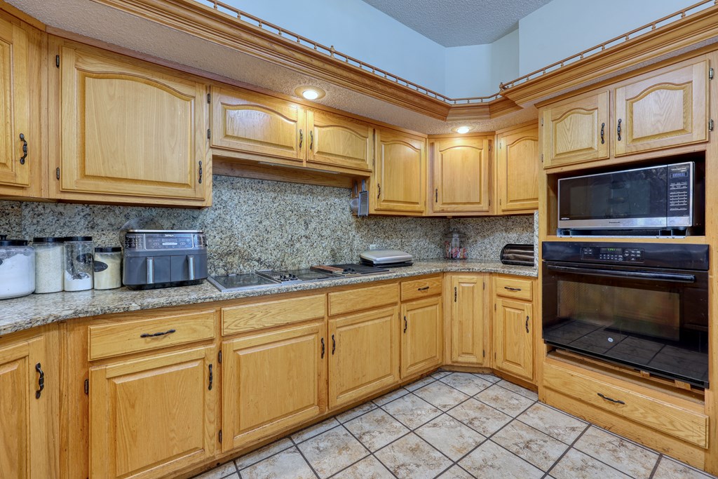 5135 Midland Trace Midland, GA 31820 - Photo 15 of 66 a kitchen with granite countertop a stove top oven microwave and cabinets