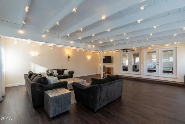 a living room with couches and kitchen view with wooden floor