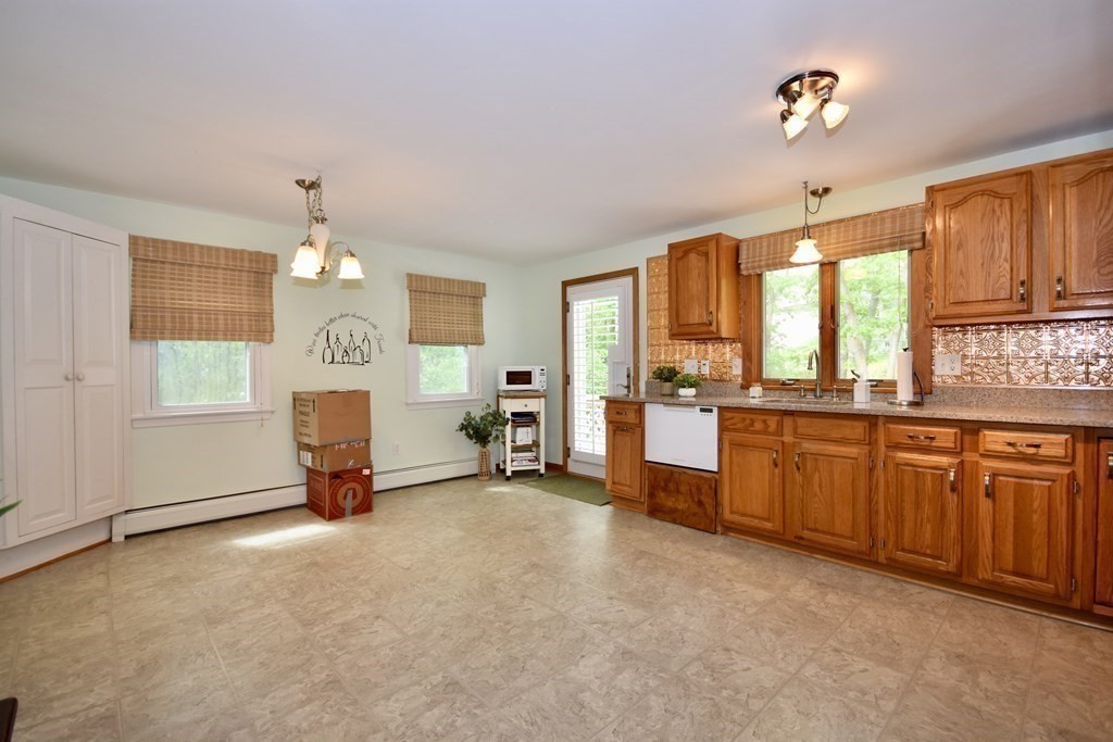 29 Tecumseh Road Bourne, MA 02562 - Photo 16 of 28 a large kitchen with stainless steel appliances granite countertop a stove a sink dishwasher and a fireplace with wooden floor