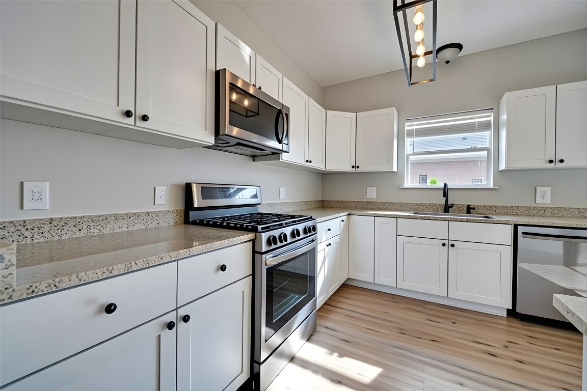 350 Carriage Way Kyle, TX 78640 - Photo 8 of 37 a kitchen with stainless steel appliances granite countertop a sink a stove a microwave and wooden cabinets