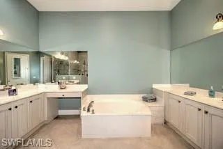 a bathroom with a tub a sink and mirror
