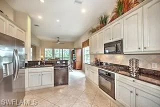 a kitchen with stainless steel appliances granite countertop a stove a sink a refrigerator and white cabinets