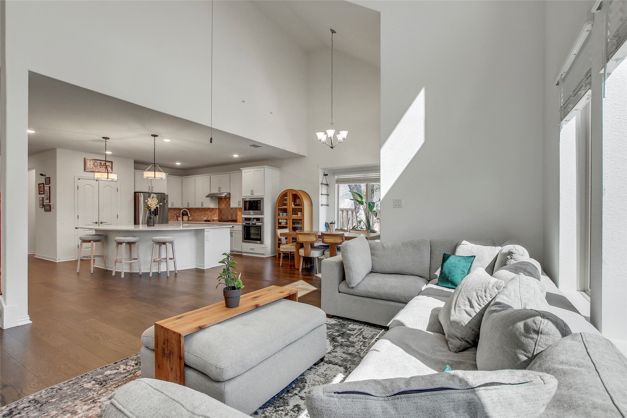 104 Millbend Road Georgetown, TX 78633 - Photo 18 of 40 Natural light streams into this open-concept living space, highlighting soaring ceilings and rich hardwood flooring.