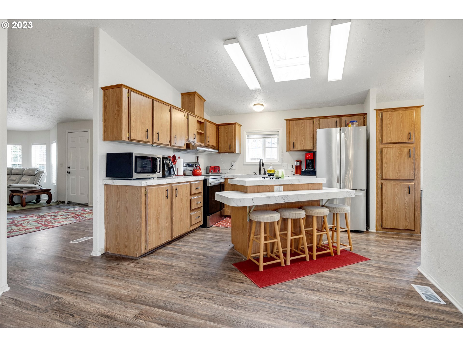 1949 Southeast Palmquist Road, Unit 17 Gresham, OR 97080 - Photo 9 of 31 a living room with stainless steel appliances kitchen island granite countertop furniture wooden floor and a kitchen view