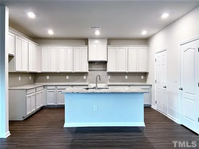 a kitchen with kitchen island granite countertop a sink cabinets and wooden floor