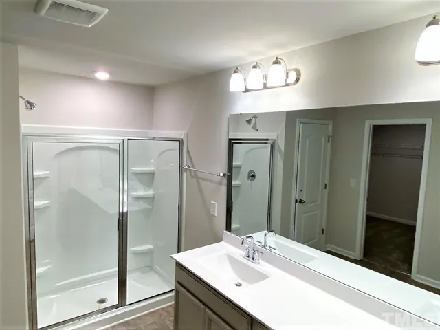 a bathroom with a sink shower and a mirror