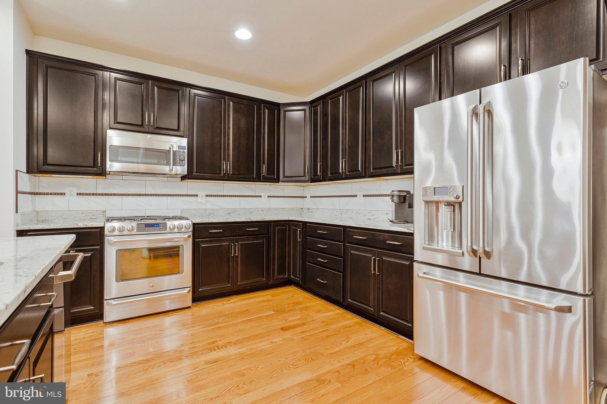 9726 Knowledge Drive Laurel, MD 20723 - Photo 7 of 54 a kitchen with stainless steel appliances granite countertop a refrigerator and a stove top oven
