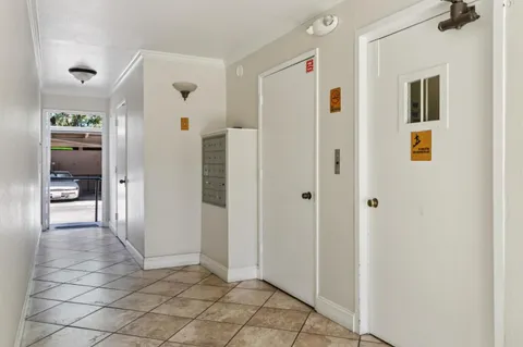 a view of a hallway with wooden floor and a bathroom