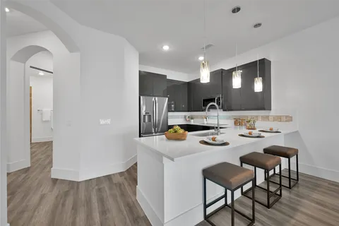 a kitchen with stainless steel appliances kitchen island granite countertop a sink and a refrigerator