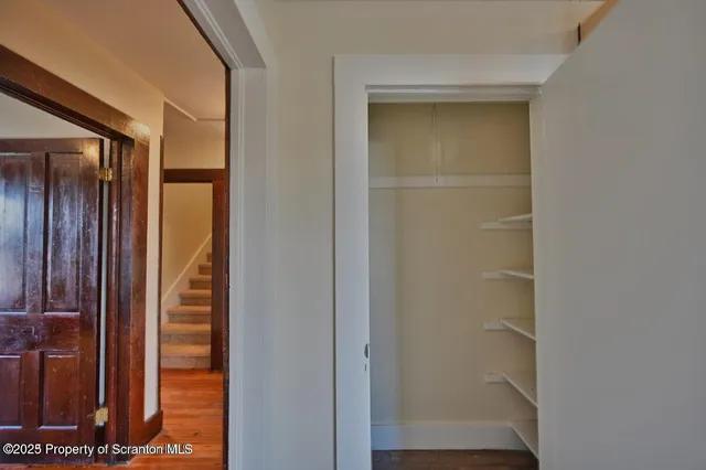 a view of a hallway with wooden floor and closet