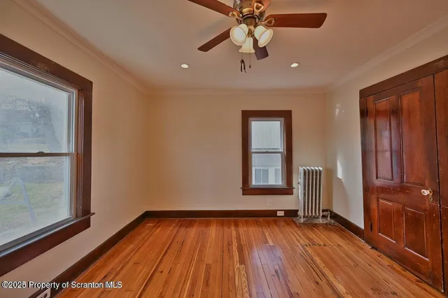 a view of an empty room with window and wooden floor