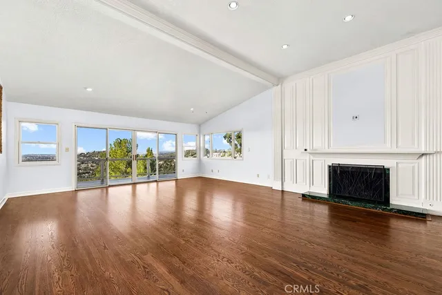 a view of an empty room with wooden floor fireplace and a window