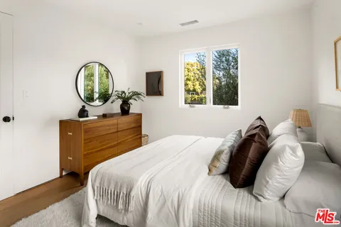 a bedroom with a bed a mirror and window