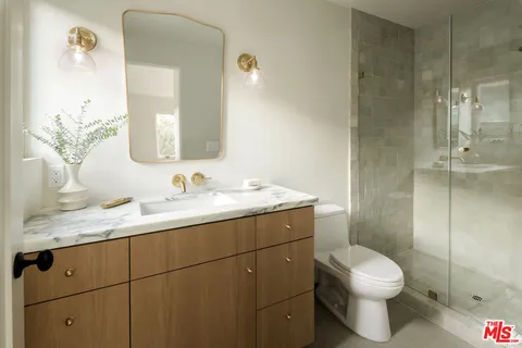 a bathroom with a granite countertop sink a toilet and a mirror