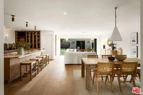 a view of a dining room and livingroom with furniture wooden floor a chandelier