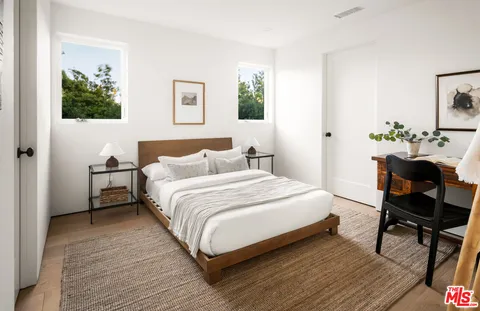 a bedroom with a bed table chair and a window