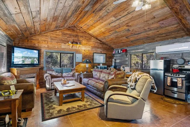 a living room with furniture a flat screen tv and floor to ceiling window