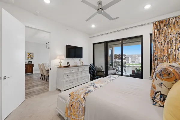 a large bedroom with a bed and a flat tv screen on dresser