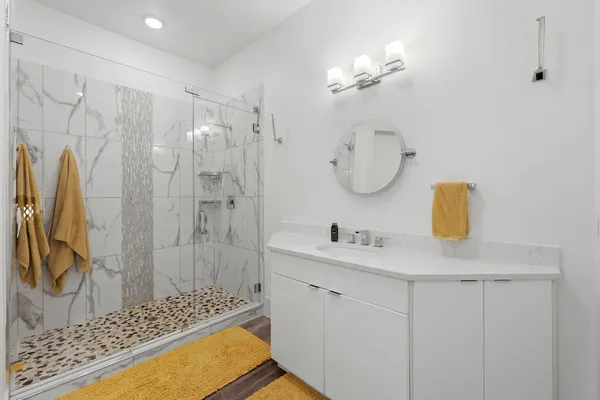 a bathroom with a sink vanity granite tub shower and a mirror