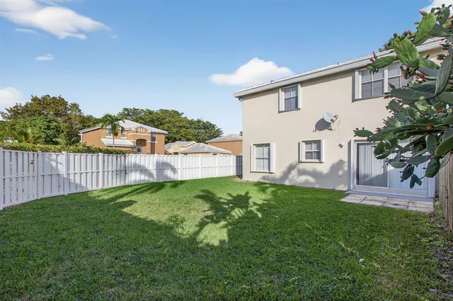 a view of backyard of house with wooden fence
