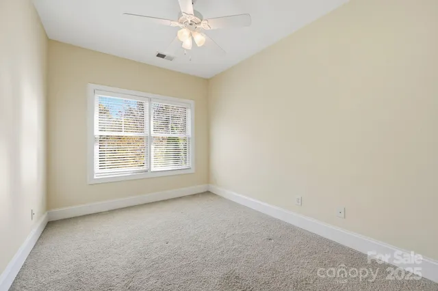 an empty room with a chandelier fan and windows