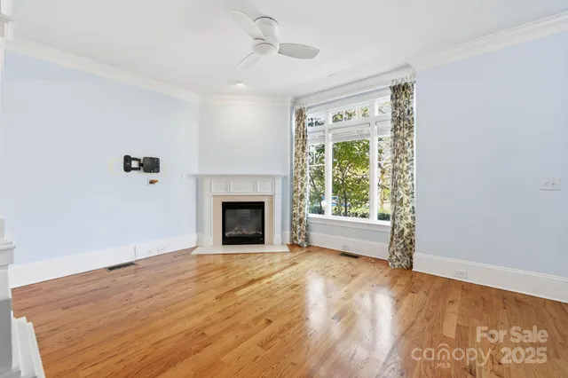 an empty room with wooden floor fireplace and windows