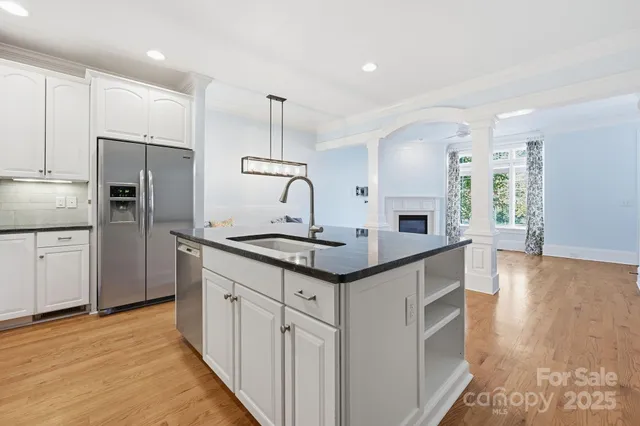 a kitchen with kitchen island granite countertop a sink a counter space appliances and cabinets