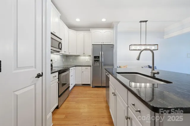 a kitchen with granite countertop a sink a counter top space and stainless steel appliances