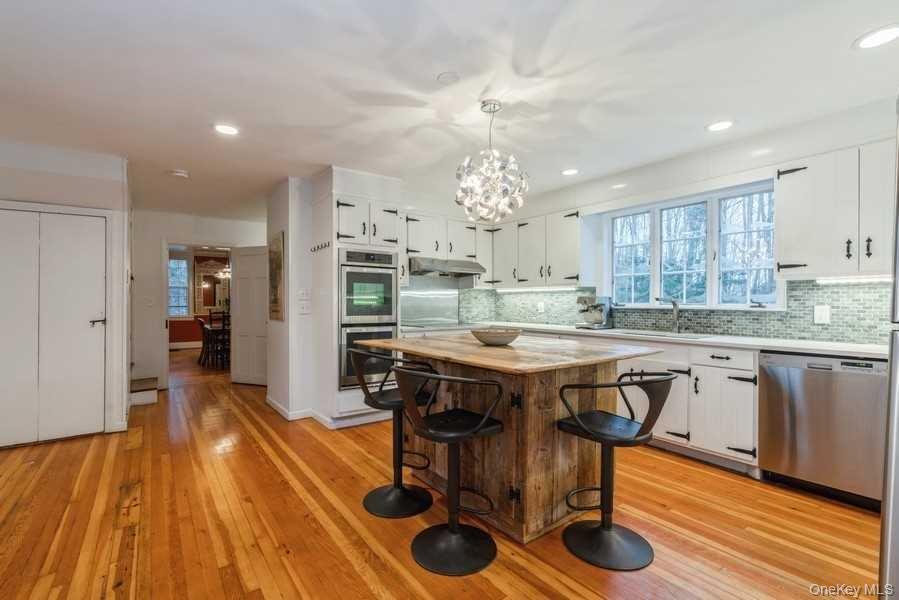 1141 Beekman Road Hopewell Junction, NY 12533 - Photo 6 of 36 a dining hall with stainless steel appliances granite countertop a stove a refrigerator a sink dishwasher with a dining table and chairs with wooden floor