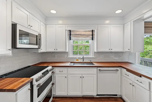 a kitchen with stainless steel appliances granite countertop white cabinets sink and window