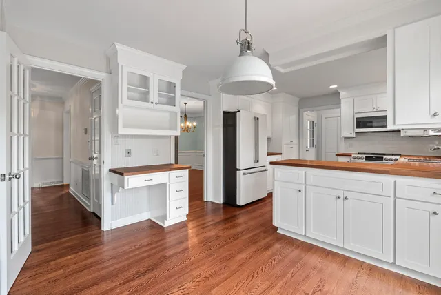 a kitchen with stainless steel appliances a refrigerator a sink dishwasher a stove and white cabinets with wooden floor