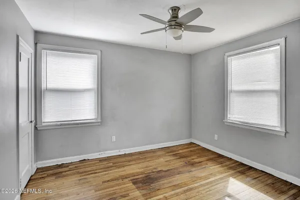 a view of an empty room with wooden floor and a window