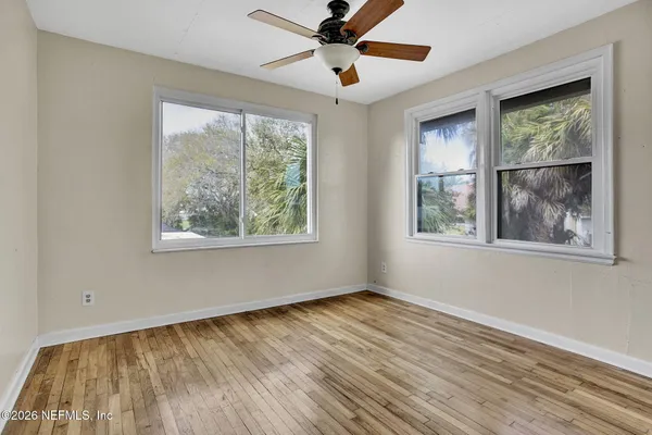 a view of an empty room with wooden floor and a window