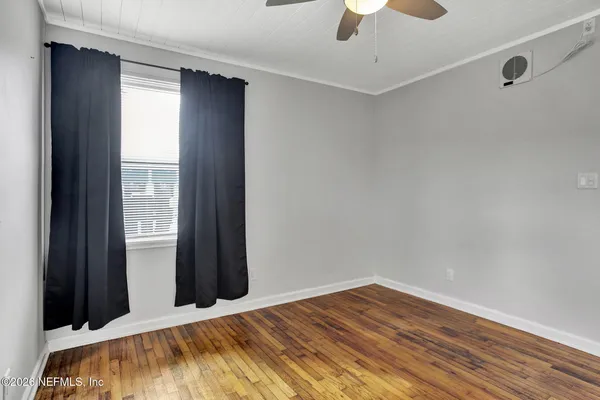 an empty room with wooden floor and windows