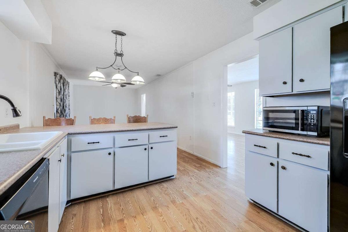 412 Rothwell Street Pooler, GA 31322 - Photo 13 of 32 a kitchen with stainless steel appliances granite countertop a sink cabinets and wooden floor