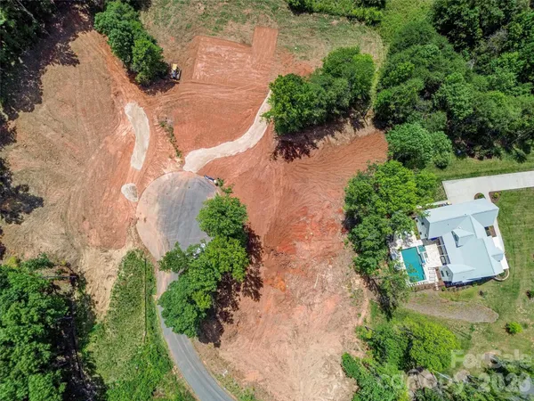 an aerial view of a house with a yard and trees all around