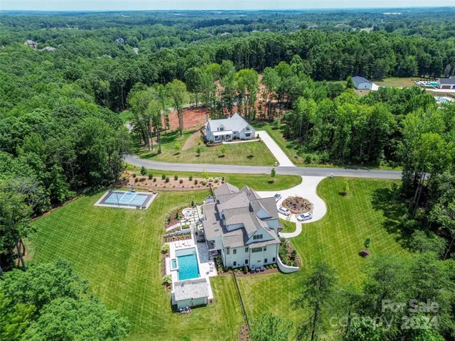 an aerial view of a house with swimming pool big yard and large trees